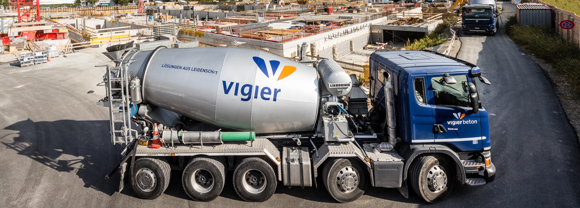 Ein Betontransport in einem blau-silbernen Betonmischer-LKW von Vigier Beton.