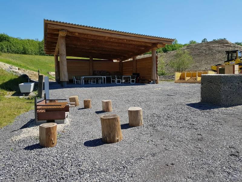 Ein Holz-Vorstand mit einigen Baumstäm-Hocker und einem Betonplatz